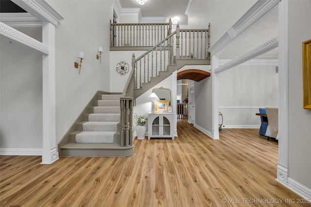 entrance foyer featuring crown molding, wood-type flooring, and a high ceiling