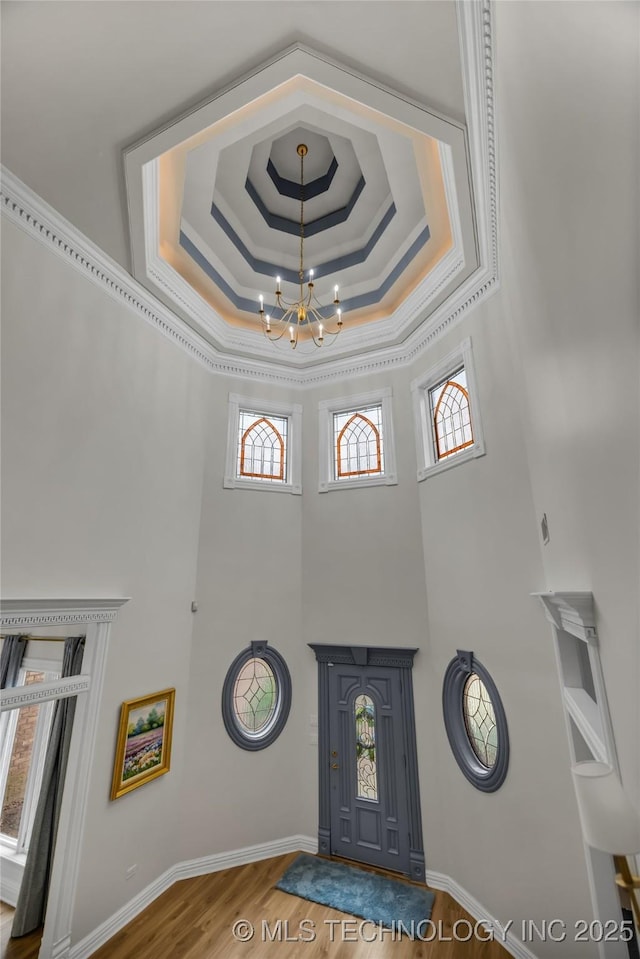 entryway featuring hardwood / wood-style flooring, a healthy amount of sunlight, a tray ceiling, and a chandelier