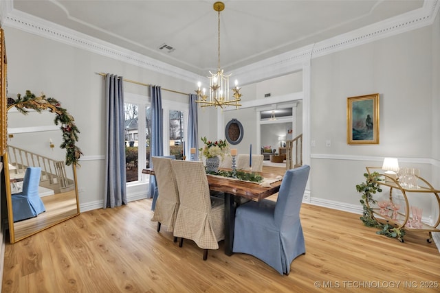 dining area featuring crown molding, an inviting chandelier, and light hardwood / wood-style flooring