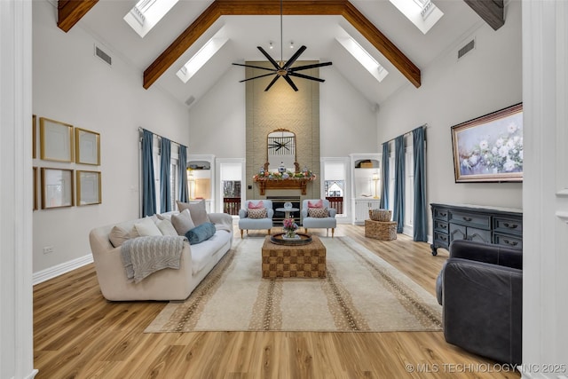 living room with ceiling fan, beam ceiling, a skylight, and wood-type flooring