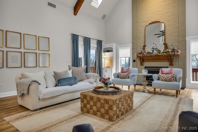 living room featuring hardwood / wood-style floors, beam ceiling, a skylight, and high vaulted ceiling