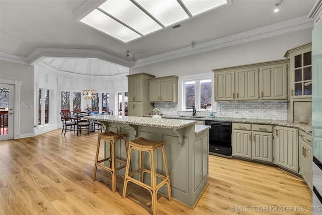 kitchen with light hardwood / wood-style flooring, ornamental molding, dishwasher, a kitchen island, and pendant lighting