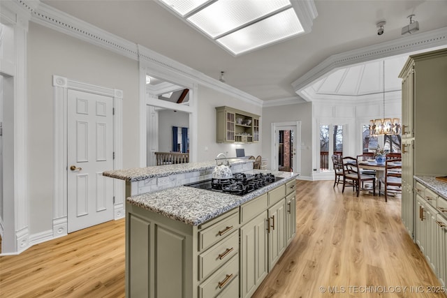 kitchen featuring pendant lighting, crown molding, black gas cooktop, a kitchen island, and light wood-type flooring