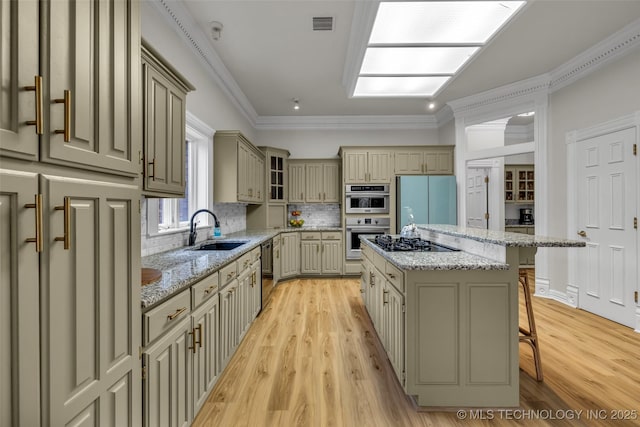 kitchen featuring a breakfast bar, sink, a center island, light stone countertops, and black appliances