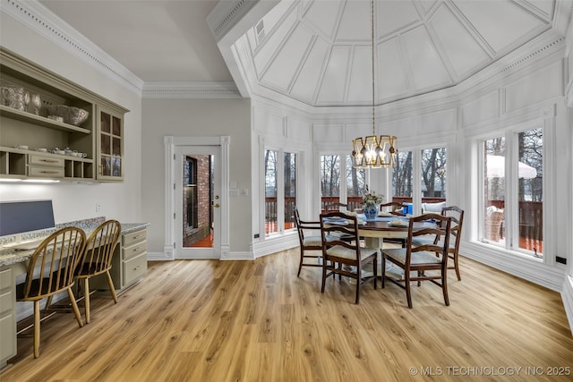 dining room featuring an inviting chandelier, built in desk, ornamental molding, and light hardwood / wood-style floors