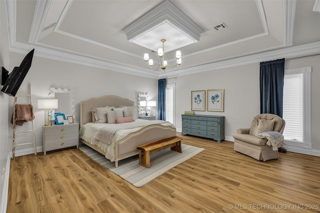 bedroom featuring an inviting chandelier, a tray ceiling, light hardwood / wood-style floors, and crown molding