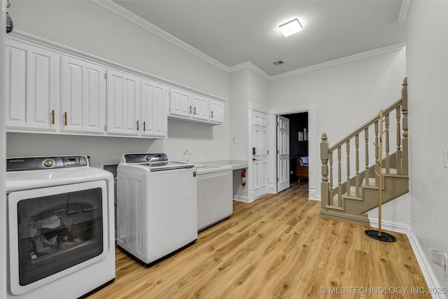 laundry room with separate washer and dryer, ornamental molding, cabinets, and light wood-type flooring