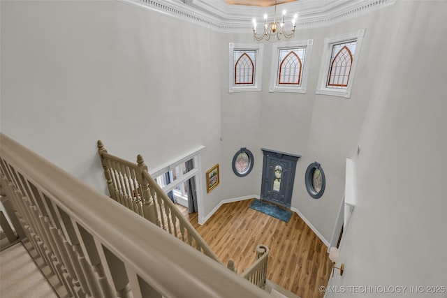 entryway with crown molding, wood-type flooring, a chandelier, and a high ceiling