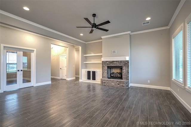 unfurnished living room featuring a fireplace, dark hardwood / wood-style flooring, ornamental molding, ceiling fan, and french doors