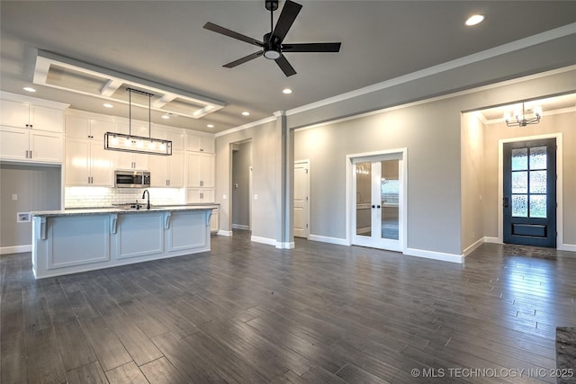 kitchen with white cabinetry, crown molding, a center island with sink, and pendant lighting