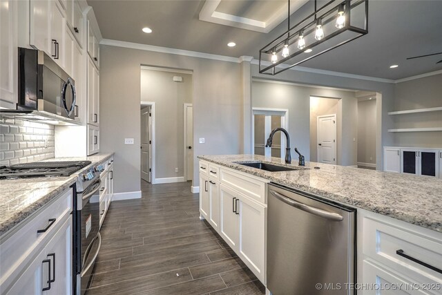 kitchen featuring appliances with stainless steel finishes, pendant lighting, white cabinetry, sink, and light stone counters