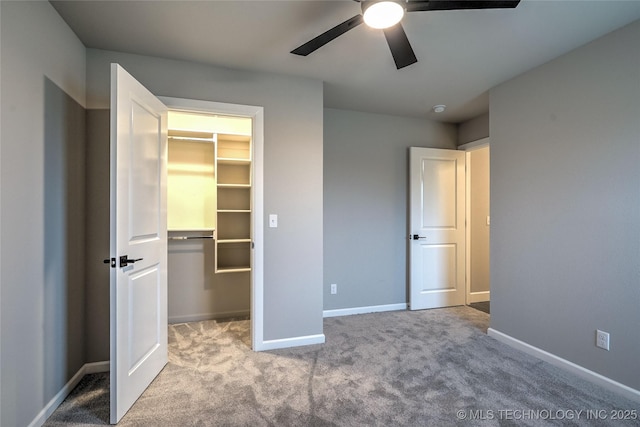 unfurnished bedroom featuring ceiling fan, a walk in closet, a closet, and light carpet