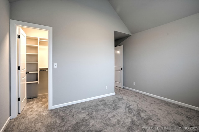 unfurnished bedroom featuring a walk in closet, lofted ceiling, a closet, and carpet