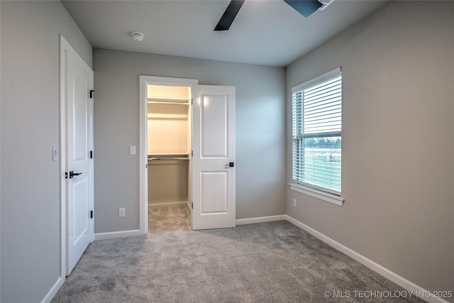 unfurnished bedroom featuring a walk in closet, light carpet, ceiling fan, and a closet