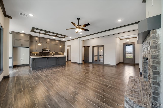 unfurnished living room with ceiling fan, ornamental molding, dark hardwood / wood-style floors, and sink