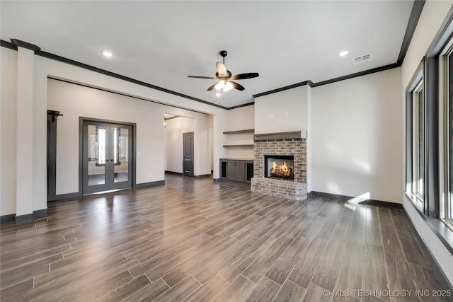 unfurnished living room featuring a fireplace, dark hardwood / wood-style flooring, ornamental molding, ceiling fan, and french doors