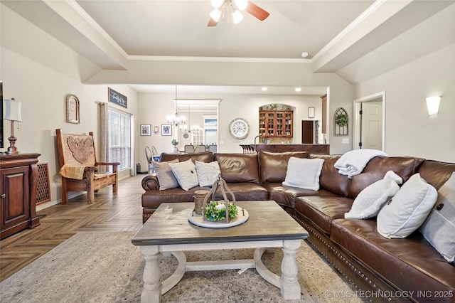 living room with parquet flooring, ornamental molding, and ceiling fan with notable chandelier