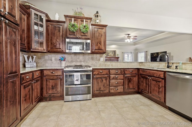 kitchen featuring light stone countertops, appliances with stainless steel finishes, ceiling fan, and decorative backsplash