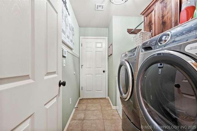 washroom featuring cabinets, light tile patterned floors, and washing machine and clothes dryer