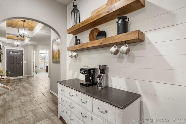 kitchen with hanging light fixtures, white cabinetry, a notable chandelier, and a tray ceiling