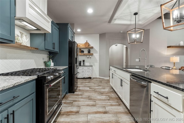 kitchen featuring blue cabinetry, premium range hood, sink, pendant lighting, and stainless steel appliances