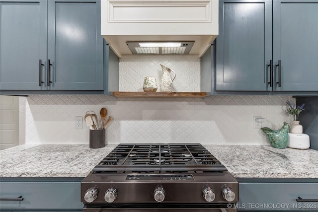 kitchen with light stone counters, blue cabinets, gas range oven, and backsplash