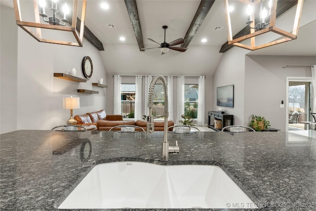 kitchen featuring sink, vaulted ceiling with beams, dark stone counters, and ceiling fan