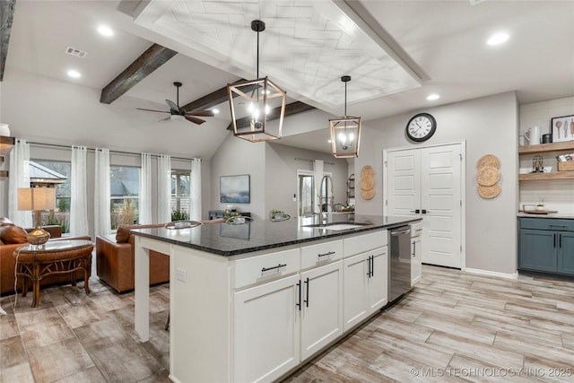 kitchen with sink, white cabinetry, hanging light fixtures, a center island with sink, and dark stone countertops