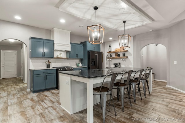 kitchen featuring blue cabinets, a kitchen bar, decorative backsplash, light hardwood / wood-style floors, and stainless steel appliances