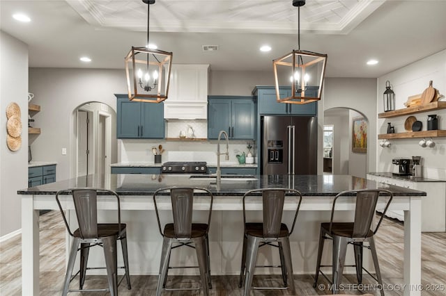 kitchen with blue cabinets, high quality fridge, sink, and a breakfast bar