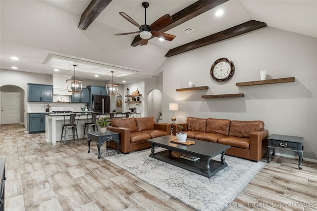 living room with ceiling fan, light hardwood / wood-style floors, and vaulted ceiling with beams