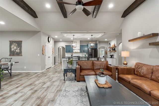 living room with ceiling fan, light hardwood / wood-style floors, and beamed ceiling