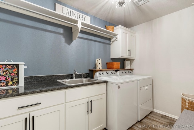 washroom with cabinets, independent washer and dryer, wood-type flooring, and sink