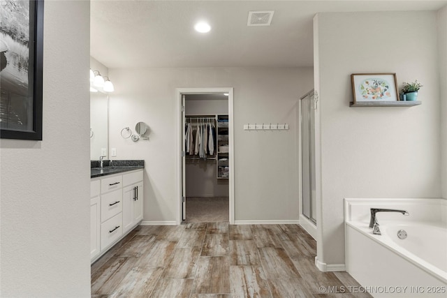 bathroom featuring vanity, hardwood / wood-style flooring, and plus walk in shower