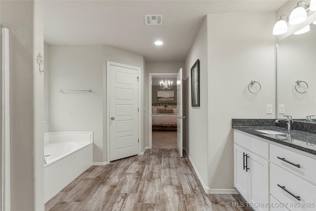 bathroom with hardwood / wood-style flooring, a bathing tub, and vanity