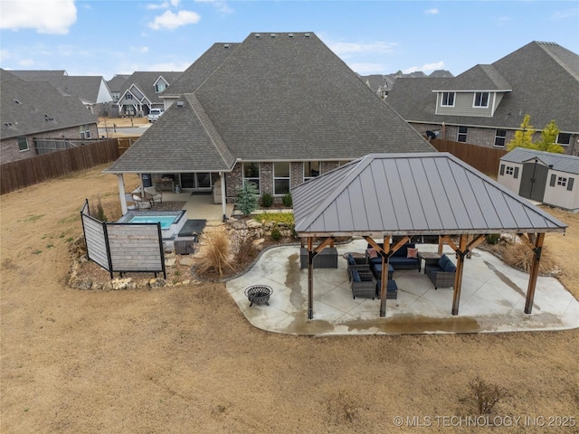 rear view of house featuring a gazebo, a storage shed, an outdoor living space, and a patio area