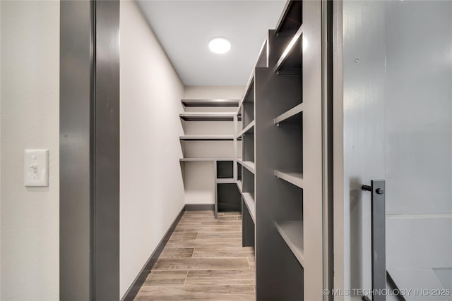 walk in closet with light hardwood / wood-style flooring