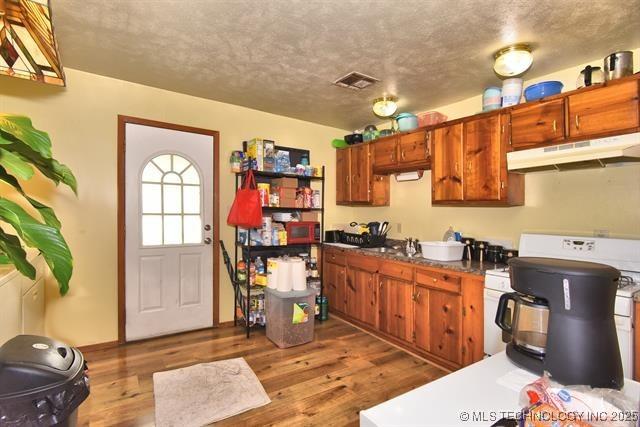 kitchen with stove, hardwood / wood-style floors, and a textured ceiling