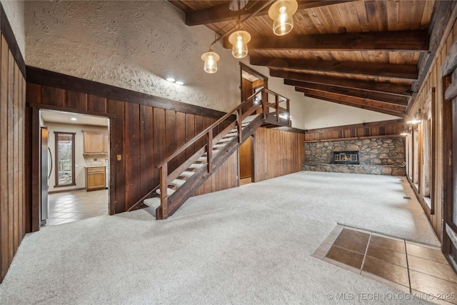 unfurnished living room with light carpet, beamed ceiling, and wood walls