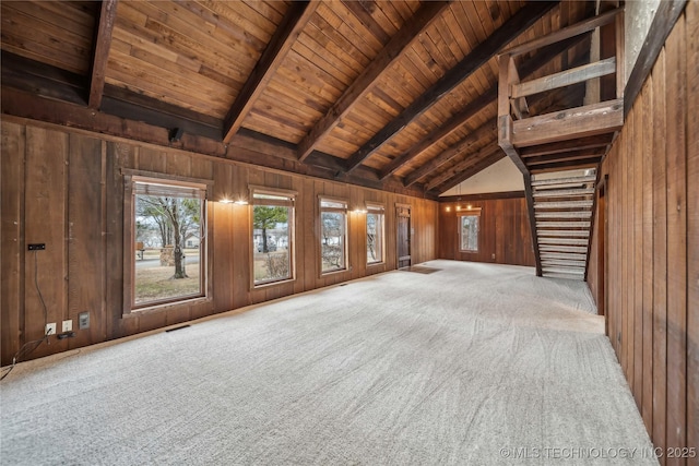 unfurnished living room with wooden walls, wooden ceiling, lofted ceiling with beams, and carpet flooring