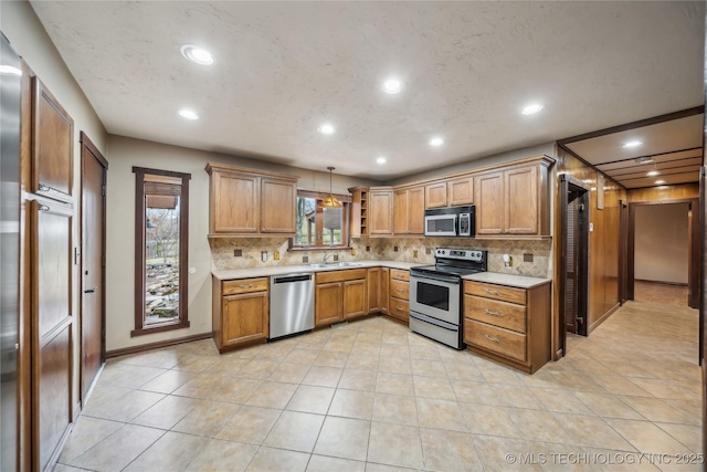 kitchen with tasteful backsplash, appliances with stainless steel finishes, light tile patterned flooring, and hanging light fixtures