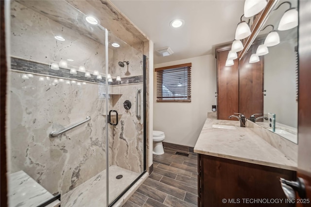 bathroom featuring toilet, vanity, and a shower with shower door