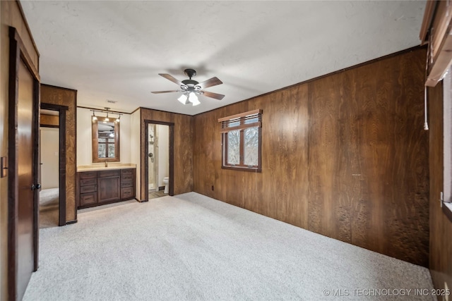 unfurnished bedroom featuring light colored carpet and wooden walls