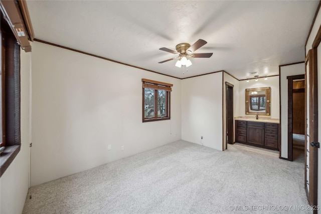 unfurnished bedroom with connected bathroom, sink, light carpet, ornamental molding, and ceiling fan