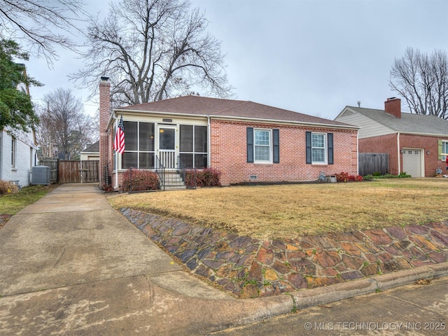 view of front of house featuring a garage, a sunroom, a front yard, and central AC unit