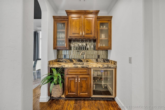 bar featuring ornamental molding, stone countertops, sink, and beverage cooler