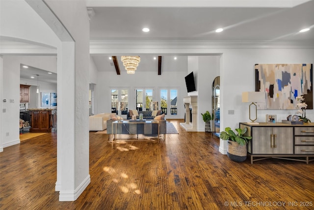 foyer entrance with dark wood-type flooring, ornamental molding, and beam ceiling