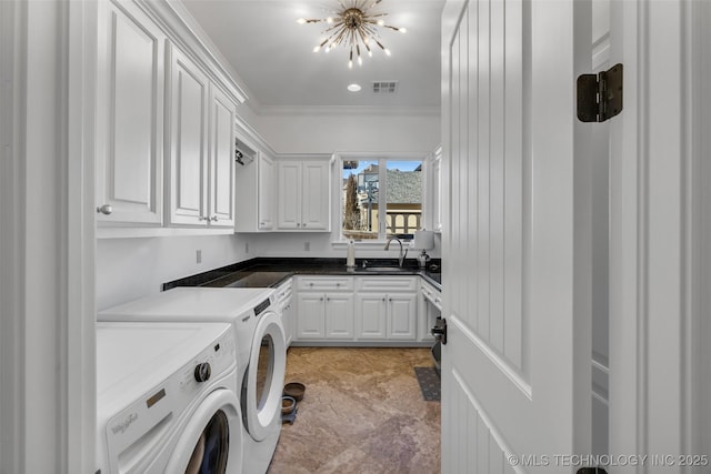 clothes washing area with sink, a chandelier, cabinets, ornamental molding, and washing machine and dryer