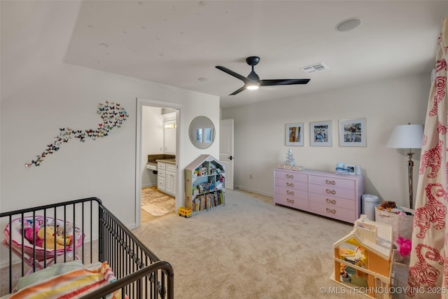 bedroom featuring a crib, light carpet, and ceiling fan