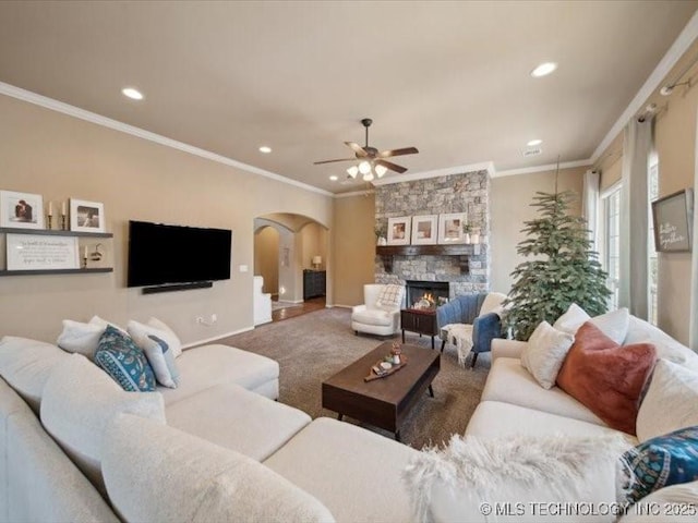 carpeted living room featuring a fireplace, ornamental molding, and ceiling fan